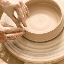 Hände arbeiten mit nassem Ton auf einer Drehscheibe