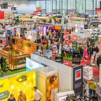 Foto der Messehalle mit verschiedenen Ständen und Aussteller*innen
