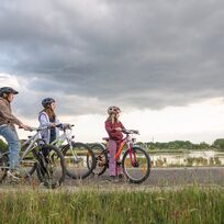 Drei Kinder sitzen auf ihren Fahrrädern in der Natur.