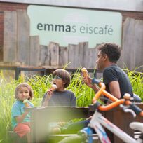 Eine Familie sitzt vor einem café und isst Eis.
