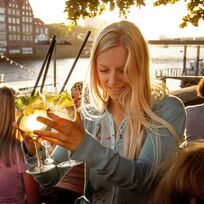 Eine Frau hält mehrere Cocktailgläser an der Hand. 