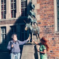 Die Bronze der Bremer Stadtmusikanten: Ein Mann und eine Frau umfassen die Vorderbeine des Esels, da dies Glück bringen soll.