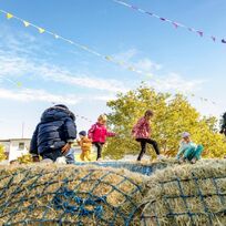 Kinder hüpfen auf einer Hüpfburg aus Heu herum