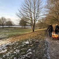 Zwei Frauen ziehen einen Bollerwagen durch eine winterliche Landschaft