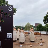 Mehrere Skulpturen stehen im Kreis. Hierbei handelt es sich um ein Kunstwerk im Rahmen der Veranstaltung "LA STRADA". Im Vordergrund steht ein Schild, auf dem QR-Codes zu sehen sind.