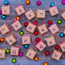 Viele kleine Päckchen mit Nummern für den Adventskalender sind auf einem Tisch verteilt. 