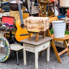 Eine Flohmarktszene von einem Stand mit kleinen Möbeln wie Nachtschränken und einer Gitarre.