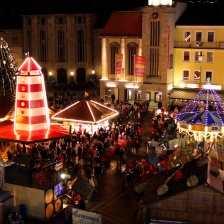 Ein Weihnachtsmarkt mit beleuchteten Buden und vielen Menschen aus der Vogelperspektive.
