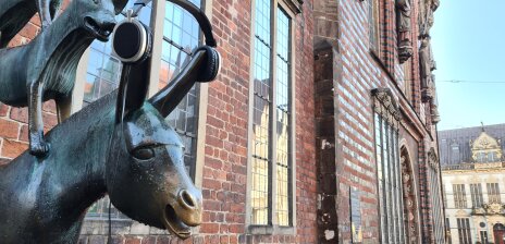 Der Esel der Statue der Bremer Stadtmusikanten trägt Kopfhörer. Darüber ist noch der Hund zu sehen