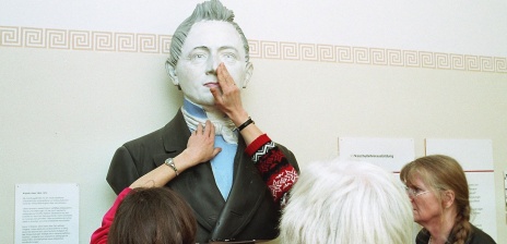 Menschen ertasten eine Skulptur in einer Ausstellung.