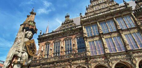 The town hall and Bremen's Roland statue from the outside. The sun is shining.