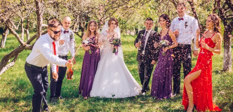 Ein Brautpaar steht mit seinen Gästen auf dem Rasen und lässt Konfetti regnen