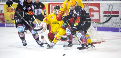 Zwei verschiedene Eishockey Teams duellieren sich vor dem Tor. 