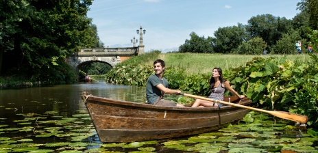 Couple in a rowboat in a pond with water lilies.