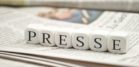Auf einer Zeitung liegen Buchstaben-Würfel die das Wort "Presse" bilden. 