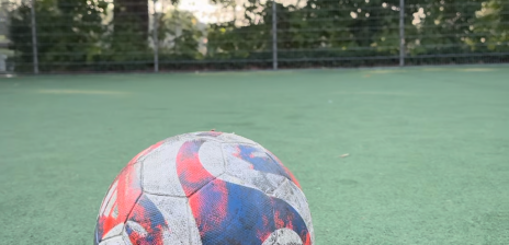 Ein Fußball liegt auf einem Fußballplatz auf dem Kunstrasen 