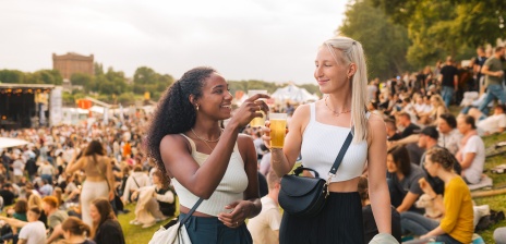 Zwei junge Frauen auf der Breminale stoßen mit einem Getränk an.