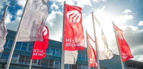 Vor dem Congress Zentrum Bremen wehen rote Fahnen mit dem Logo des Standortes