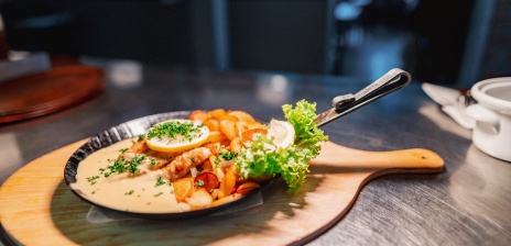 Eine gusseiserne kleine Pfanne, in dem ein Fischgericht serviert wird.