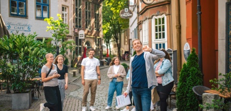 Eine Personengruppe läuft bei einer Stadtführung durch den Bremer Schnoor. Der Gästeführer erklärt etwas.