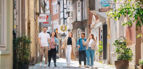 Eine Gruppe aus fünf Personen läuft durch eine schmale Gasse mit kleinen Häusern.
