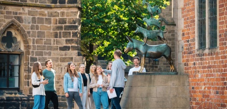 A group of people stands at the Town Musicians and is given a guided tour of the city