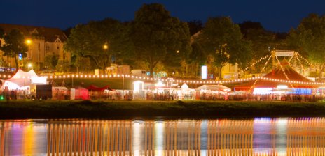 Blick auf festlich beleuchtete Festzelte zur Breminale an der Weser