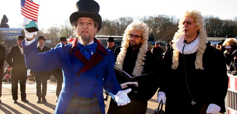 Ein Mann in einem blauen Kostüm steht vor einer Gruppe mit Männern.