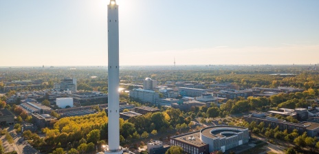Ein dünner, weißer Turm mit Spitze, durch den die Sonne durchblickt.