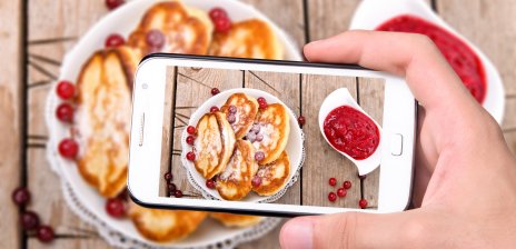 Blick durch das Kameradisplay eines Smartphones auf Pfannkuchen mit Früchten