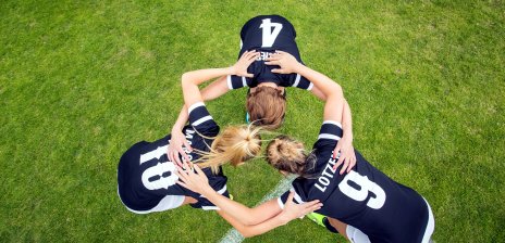 Drei Spielerinnen eines Damenteams besprechen sich in einem Kreis