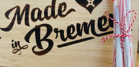 An ein Holzschild mit der eingebrannten Inschrift "Made in Bremen" stehen 5 zusammengebunde Bremer Babbeler.