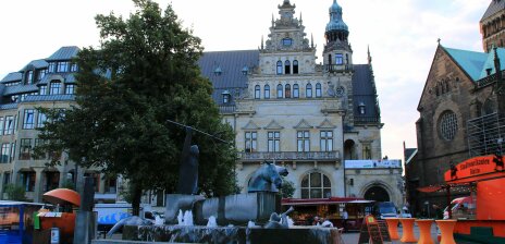 Im Hintergrund liegt das historische Gebäude der Bremer Bank. Davor reihen sich einige Marktstände sowie der Neptunbrunnen am Marktplatz.