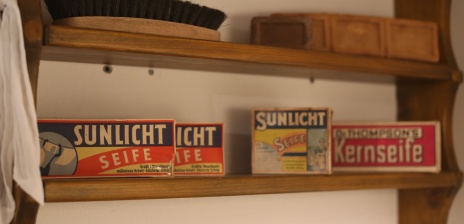 Ein altes Holzregal mit verschiedenen Seifen und Reinigungsbürste. 