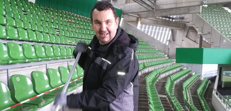 Ein Mann reinigt die Sitze eines Fußballstadions.