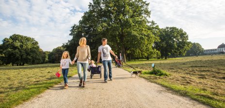 Eine Familie macht einen Spaziergang in grüner Umgebung.