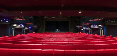 Ein großer Theatersaal mit roten Sitzreihen.