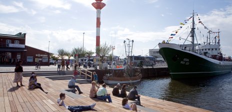 Schaufenster Fischereihafen in Bremerhaven: Menschen sitzen entspannt am Wasser.
