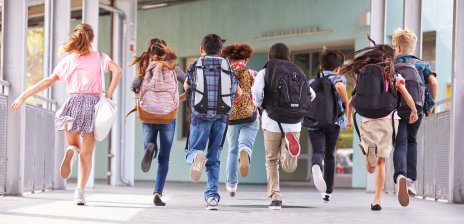 Schulkinder mit Schulranzen auf dem Rücken laufen 