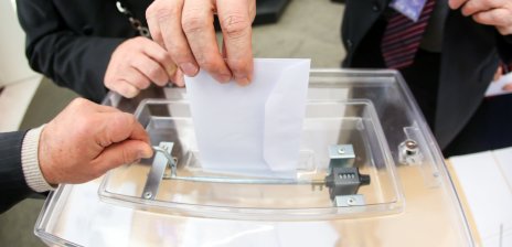 Ein Brief wird in eine Wahlurne geworfen