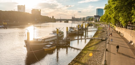 Die Flaniermeile "Schlachte" an der Weser bei Sonnenuntergang. Es befinden sich zahlreiche Schiffe auf dem Wasser. 