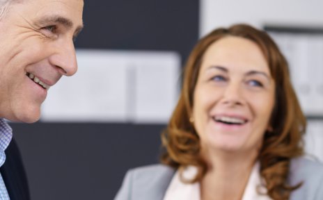 Zwei Frauen und ein Mann lachend in einem Geschäftsgespräch (Quelle: fotolia / contrastwerkstatt)