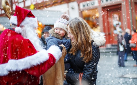Ein Nikolaus mit einem großen Beutel beschenkt ein kleines Kind. 