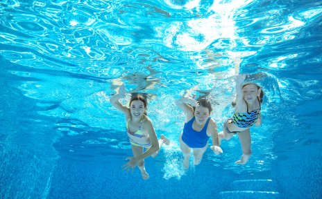 Eine Frau und zwei Mädchen aus der Unterwasserperspektive in einem Schwimmbad fotografiert. fotolia / Iuliia Sokolovska