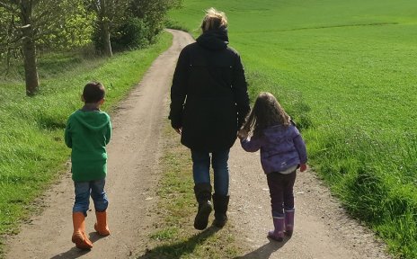Eine Frau geht mit zwei Kindern auf einem Weg spazieren, links und rechts grüne Wiese und Bäume (Foto: privat/barckhausen).