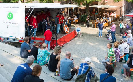 ZuschauerInnen vor einer Bühne mit Musikern auf dem Kajenmarkt.