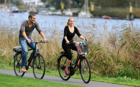Ein Mann und eine Frau fahren Rad an der Weser; Foto: WFB Wirtschaftsförderung Bremen GmbH / Ingo Wagner