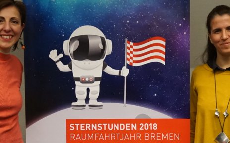Die beiden Koordinatorinnen der WIA-Bremen posieren mit einem Jungen vor einem STERNSTUNDEN2018 Roll Up.