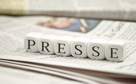 Auf einer Zeitung liegen Buchstaben-Würfel die das Wort "Presse" bilden. 