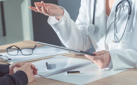 Eine Ärztin erklärt einem Patienten eine Behandlung